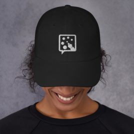 A woman wearing a black Dad hat with a white logo on it.